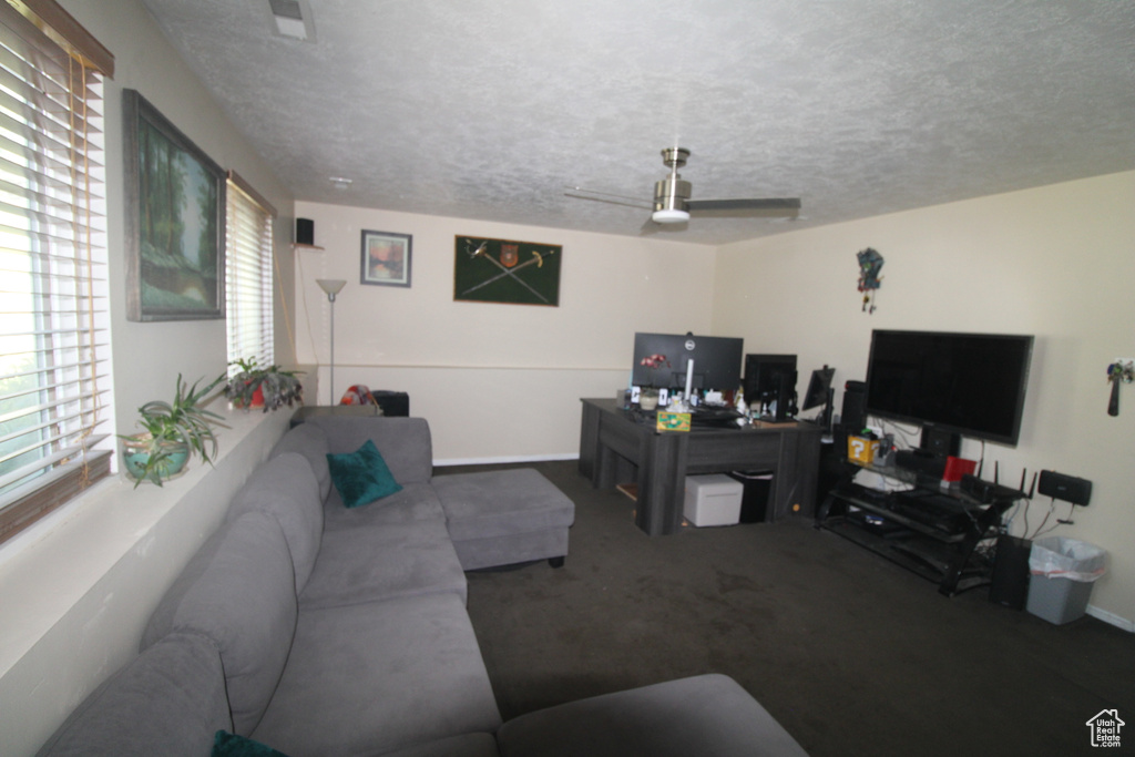 Carpeted living room featuring a textured ceiling and a ceiling fan