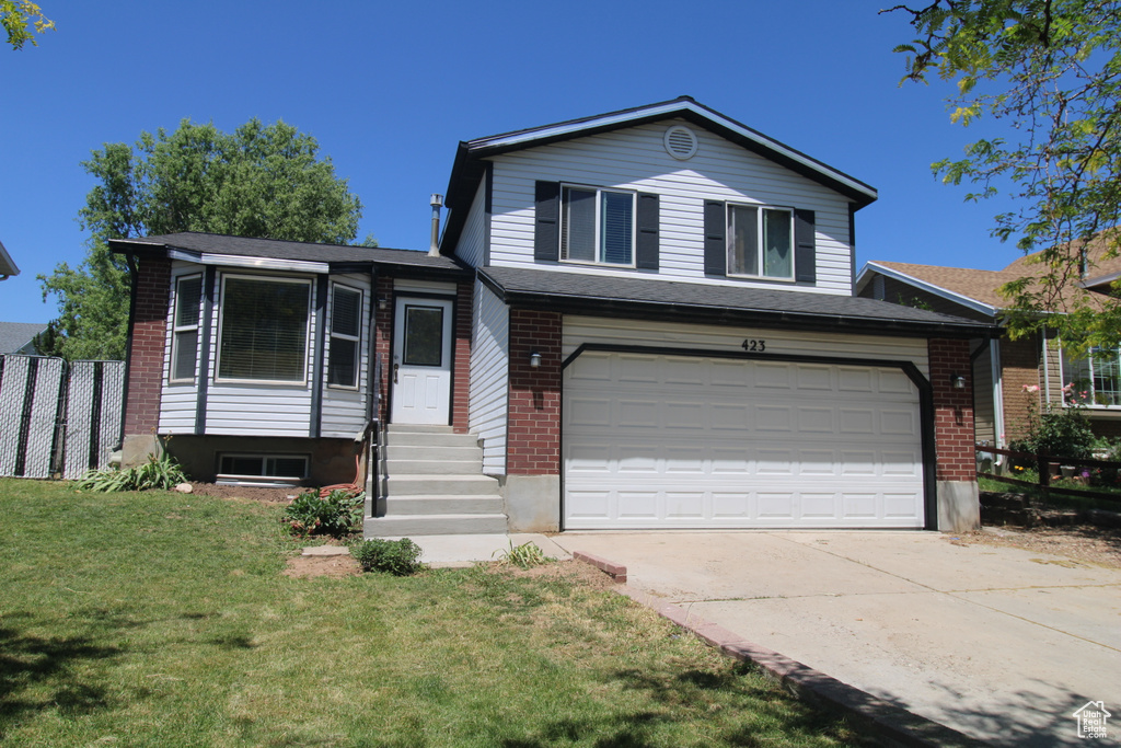 Tri-level home featuring concrete driveway, a garage, brick siding, and entry steps