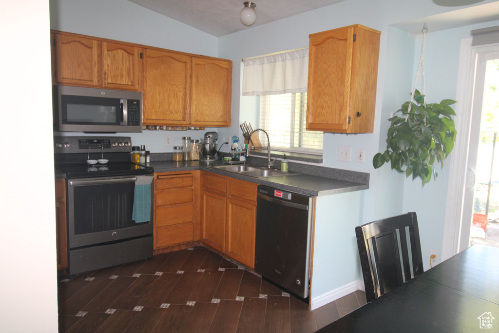 Kitchen with stainless steel appliances, dark wood-style flooring, dark countertops, and healthy amount of natural light