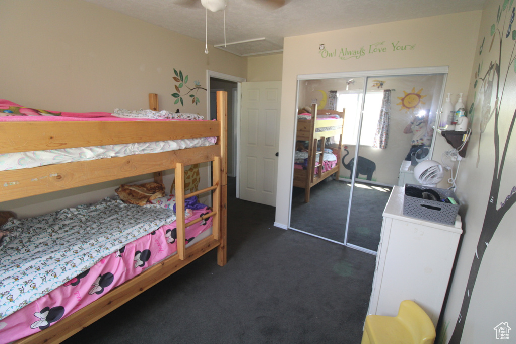 Bedroom with dark carpet, a closet, attic access, and ceiling fan