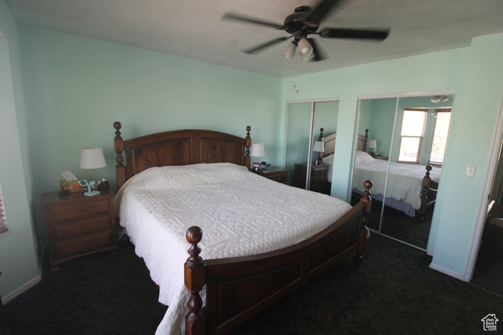 Bedroom featuring dark carpet, a ceiling fan, and two closets