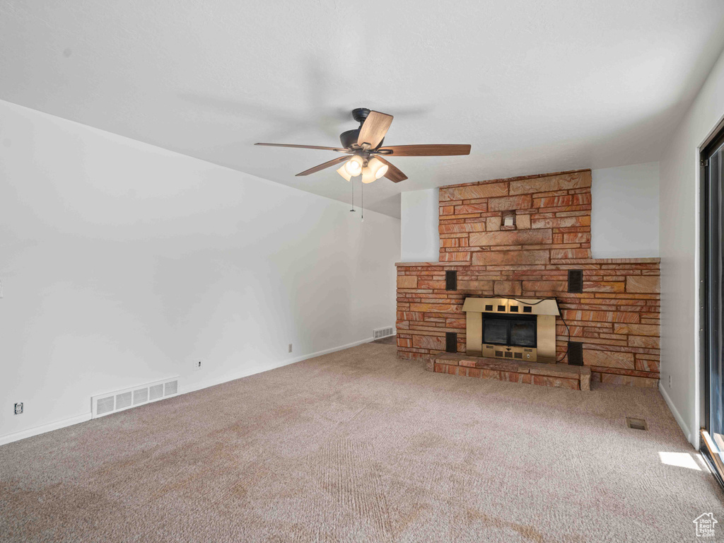 Unfurnished living room with ceiling fan, carpet, and a fireplace
