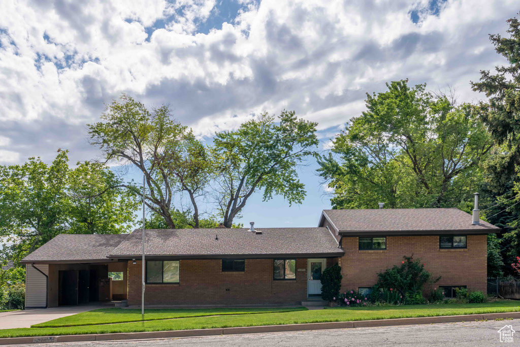 View of front of home featuring concrete driveway, a front lawn, brick siding, and a carport