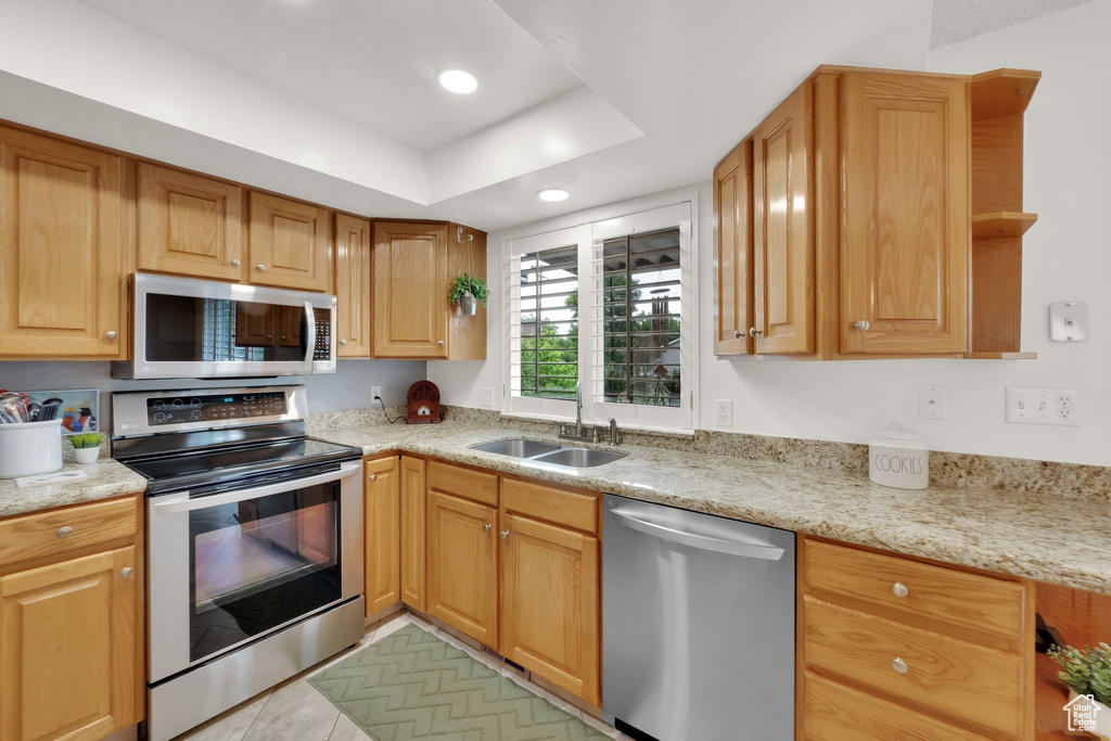 Kitchen featuring stainless steel appliances, open shelves, recessed lighting, light tile patterned floors, and light stone countertops