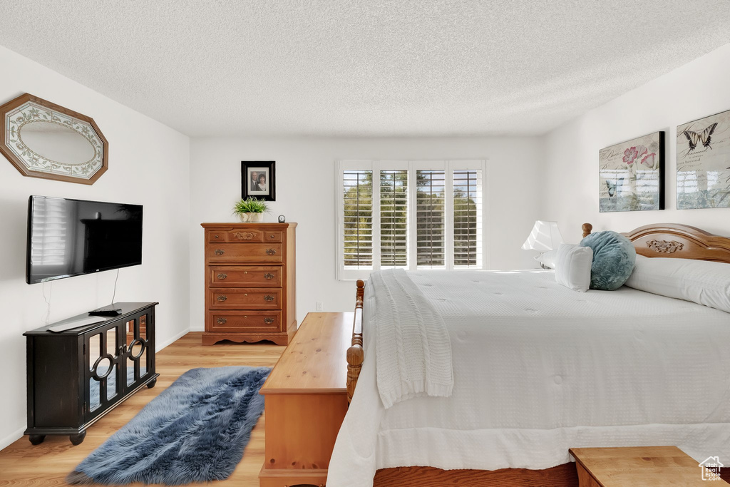 Bedroom with light wood-style floors and a textured ceiling