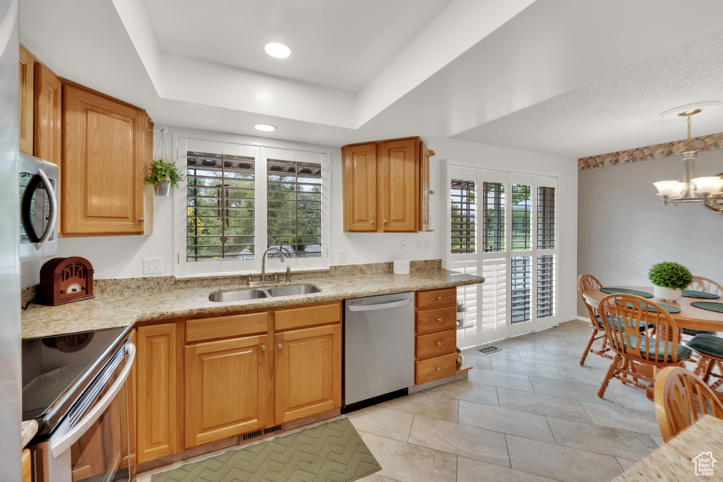 Kitchen featuring stainless steel appliances, a chandelier, light tile patterned flooring, recessed lighting, and a raised ceiling
