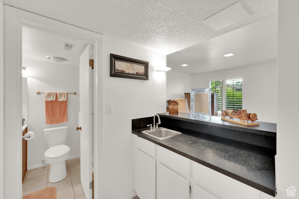 Bathroom with vanity, tile patterned flooring, and a textured ceiling