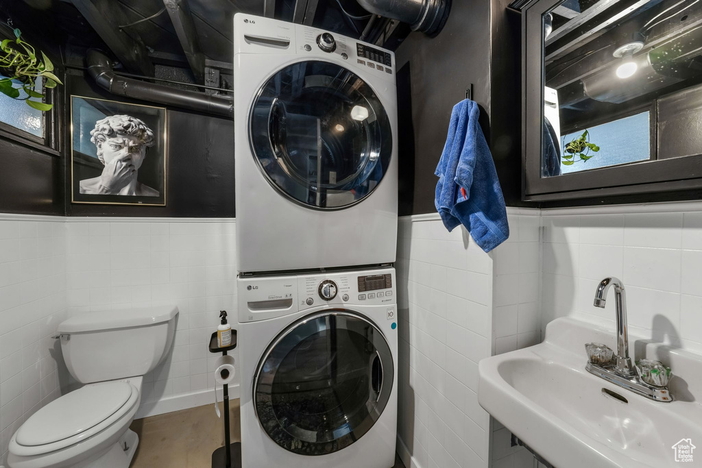 Laundry room featuring estacked washer and dryer, tile walls, and wainscoting