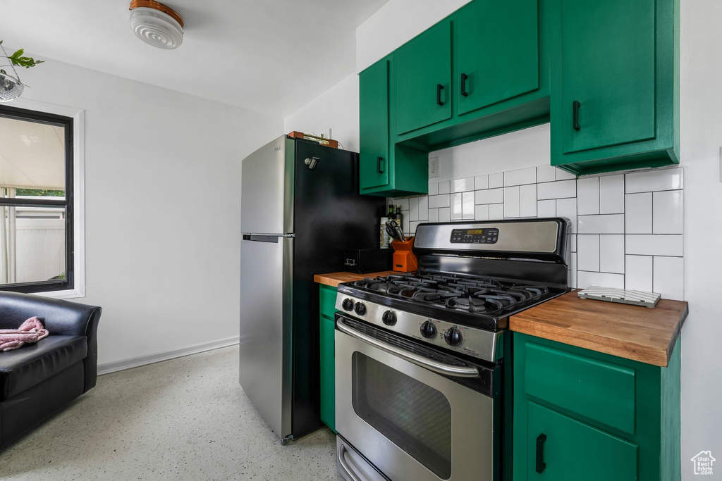 Kitchen with appliances with stainless steel finishes, wood counters, tasteful backsplash, and dark speckled floor
