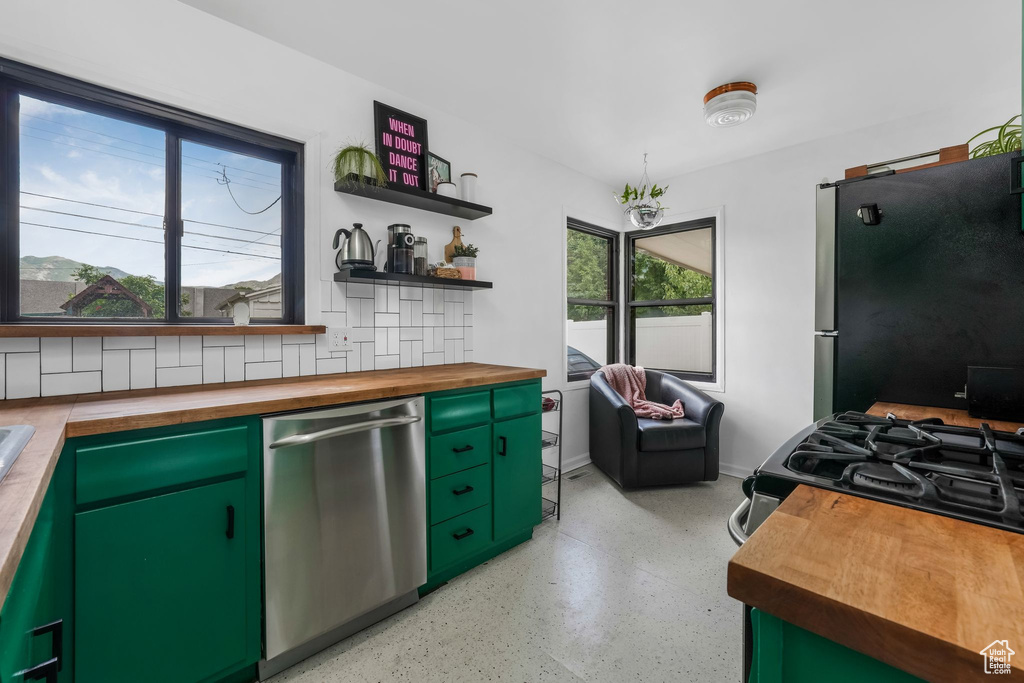 Kitchen with stainless steel appliances, wooden counters, dark aggregate flooring, and open shelves