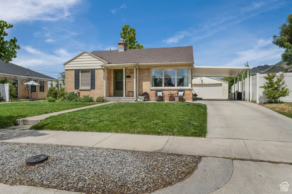 View of front facade featuring brick siding, a chimney, concrete driveway, an outdoor structure, and a garage