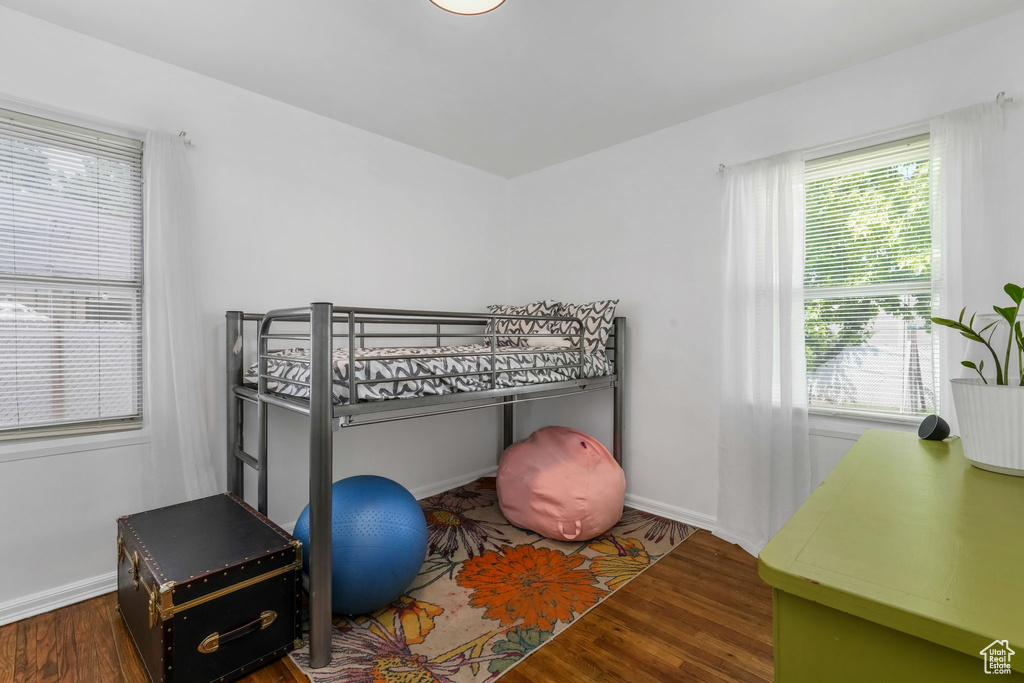 Bedroom with wood finished floors and multiple windows