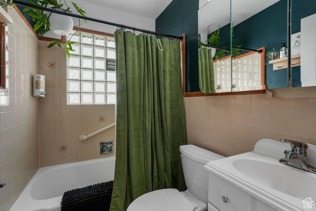 Full bathroom with shower / bath combo with shower curtain, vanity, and tile walls