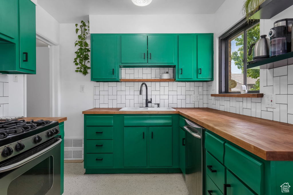 Kitchen with butcher block countertops, range with gas cooktop, and decorative backsplash