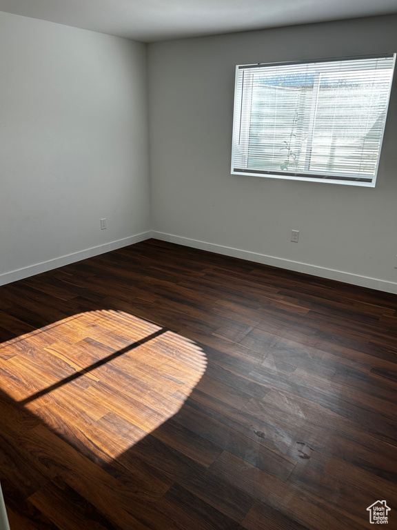 Spare room with baseboards and dark wood-style flooring