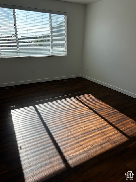 Unfurnished room featuring baseboards and dark wood-style flooring