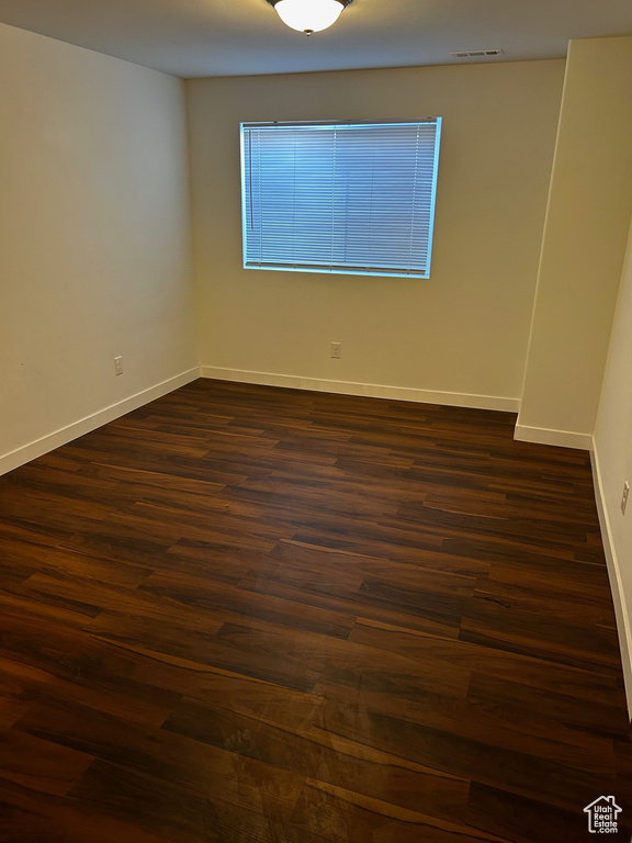 Unfurnished room with dark wood-type flooring and baseboards
