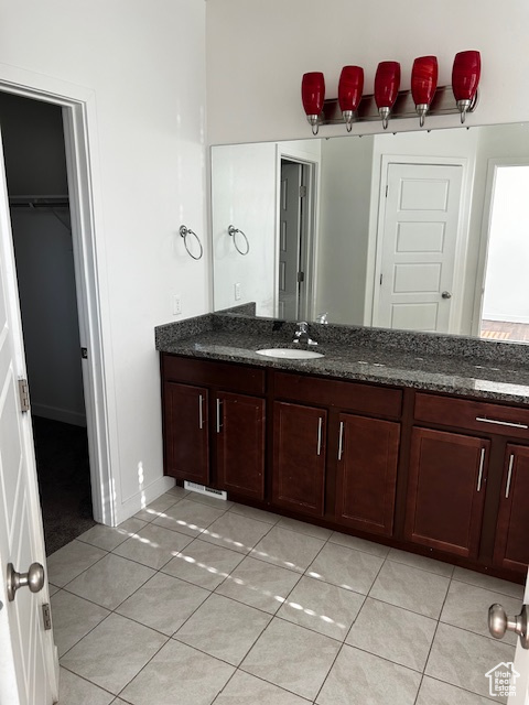 Full bath with tile patterned flooring, vanity, and a spacious closet