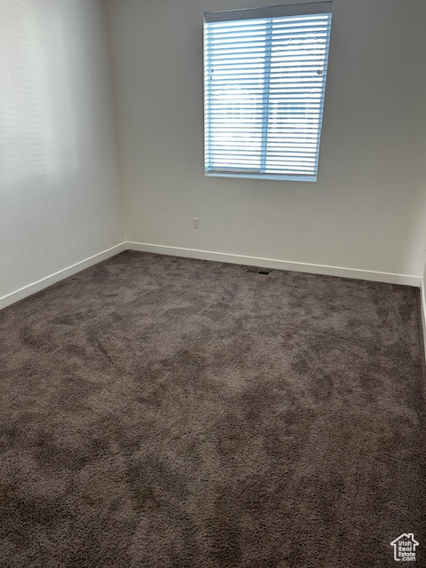 Empty room with baseboards and dark carpet