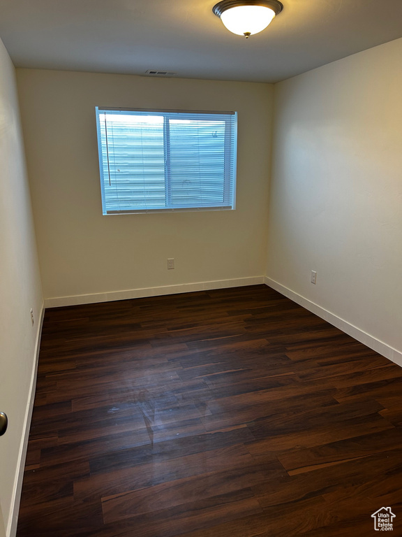 Spare room with healthy amount of natural light and dark wood-type flooring
