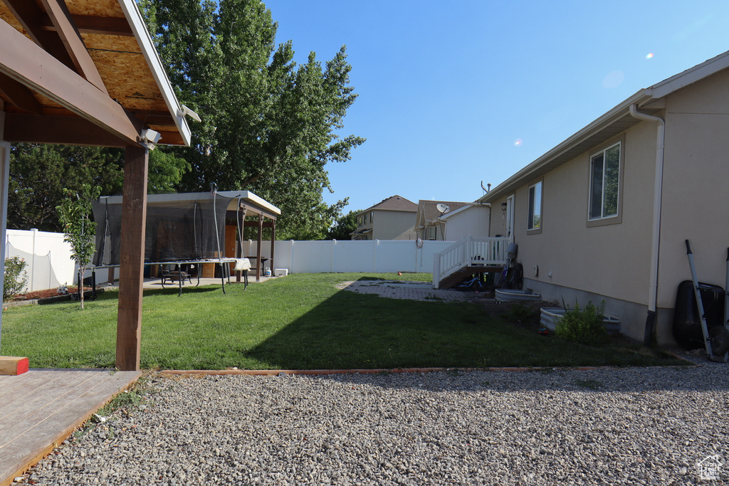 Fenced backyard with a trampoline and a patio area