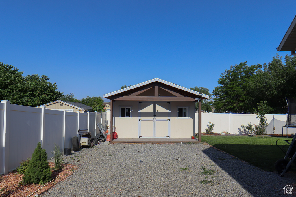 Rear view of house featuring a trampoline, a fenced backyard, and a shed