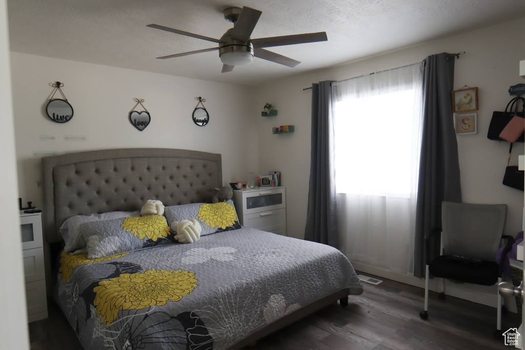 Bedroom with wood finished floors, ceiling fan, and a textured ceiling