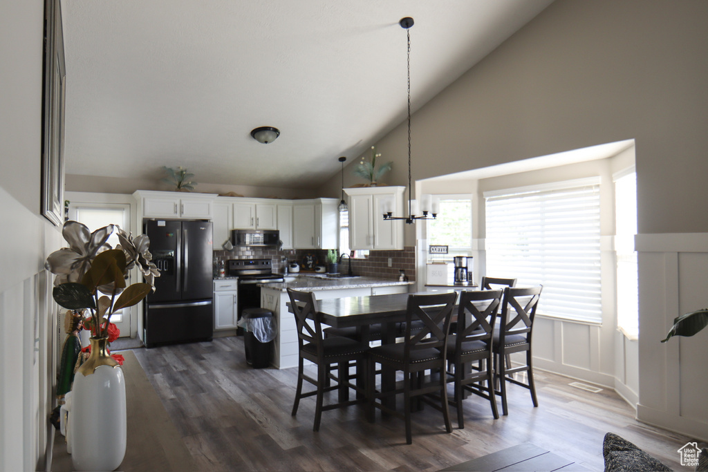 Dining area with high vaulted ceiling and dark wood-style floors