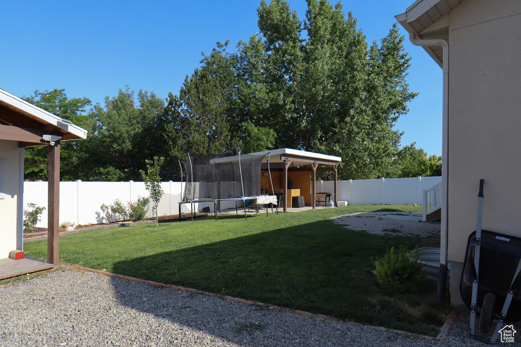 Fenced backyard with a trampoline and a patio area