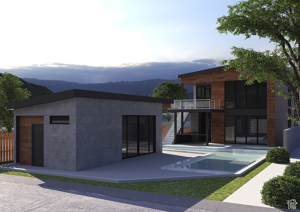 View of front facade with an outdoor pool, a patio area, a balcony, and a mountain view