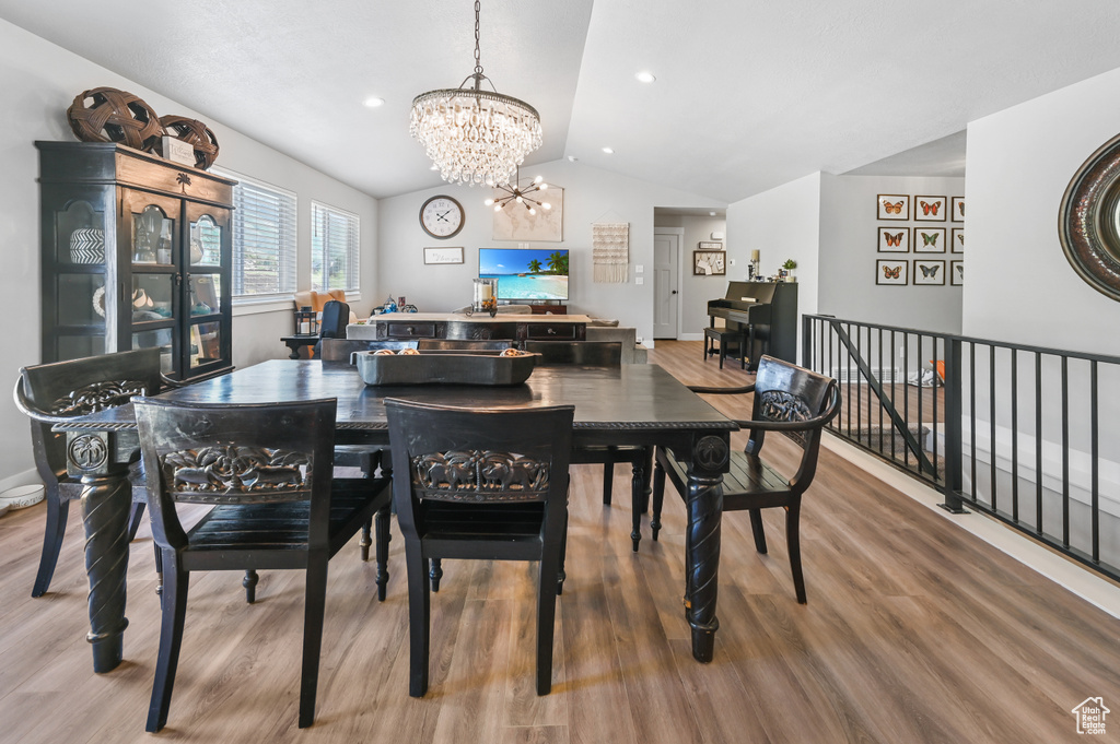 Dining room with vaulted ceiling, a chandelier, and wood finished floors