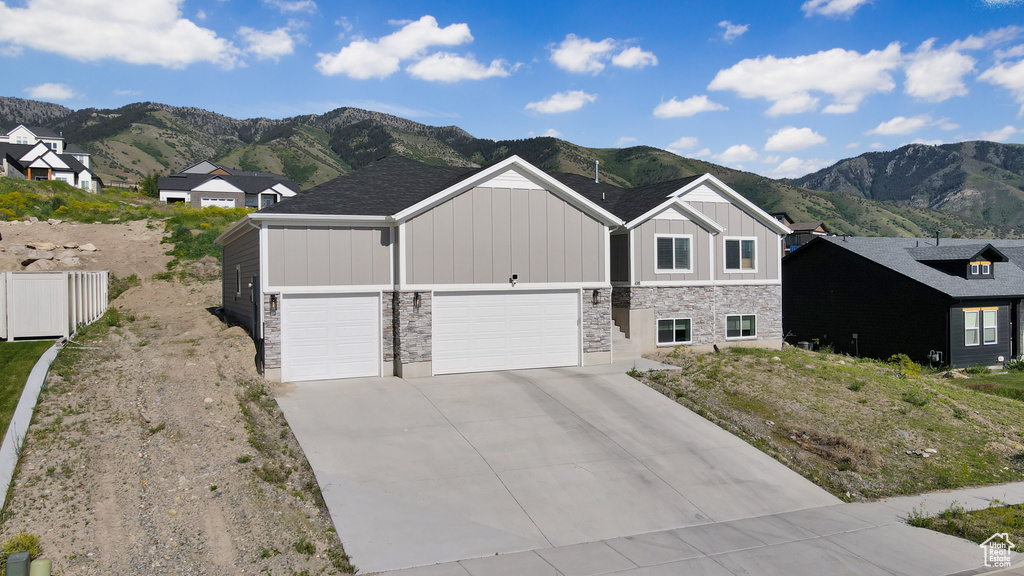 View of front of home with board and batten siding, stone siding, a mountain view, and driveway