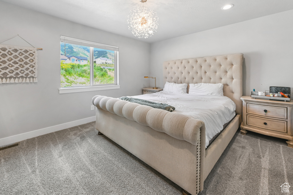 Carpeted bedroom with recessed lighting and a chandelier
