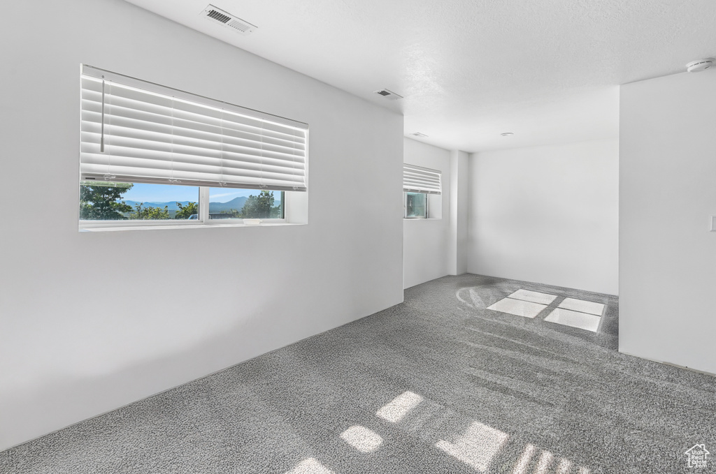 Unfurnished room featuring carpet and a smoke detector