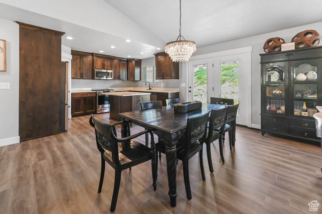 Dining area with a chandelier, vaulted ceiling, wood finished floors, and recessed lighting