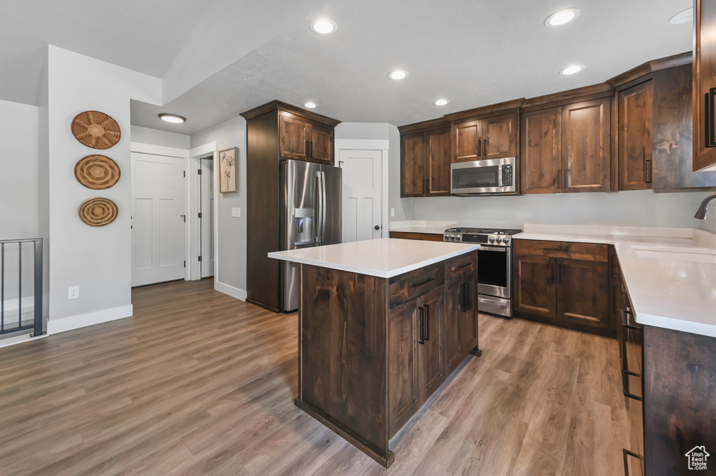 Kitchen featuring stainless steel appliances, recessed lighting, light wood-type flooring, light countertops, and a center island