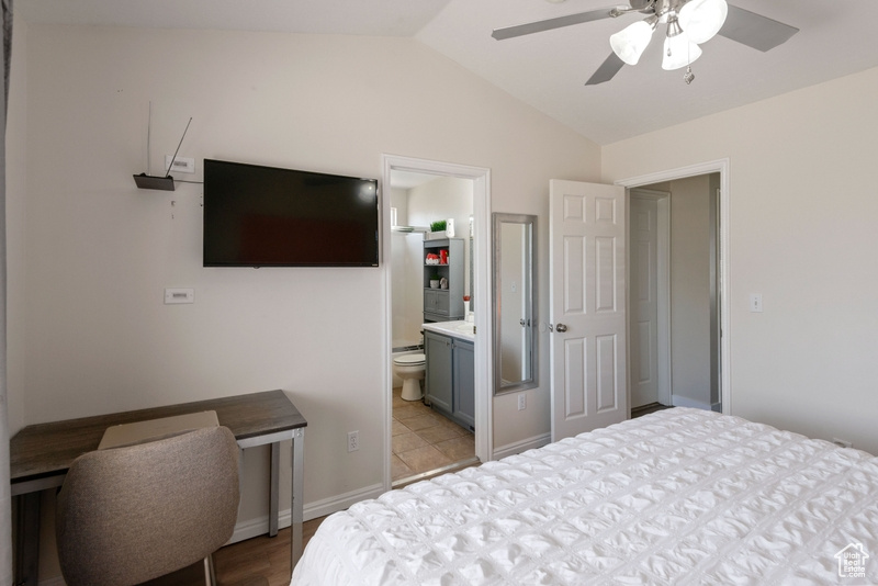 Bedroom with vaulted ceiling, light wood finished floors, a ceiling fan, and ensuite bath