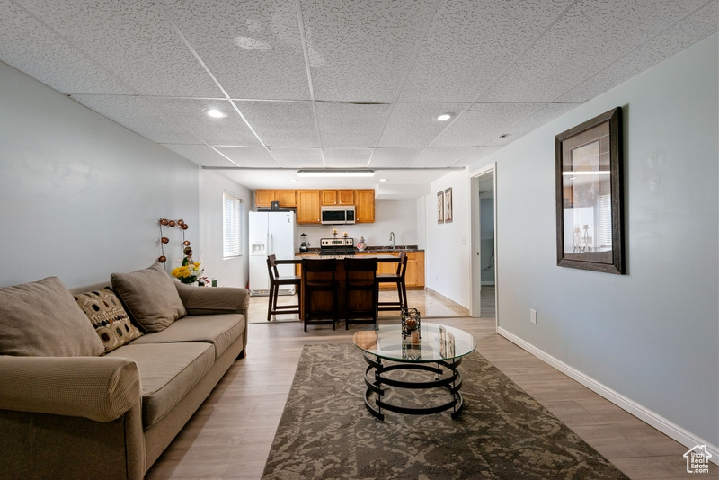 Living room featuring light wood-style floors, a drop ceiling, and recessed lighting