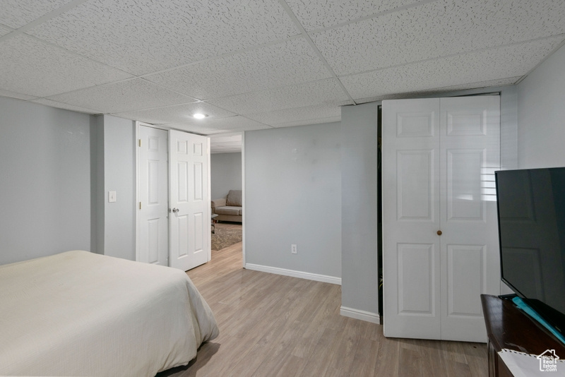 Bedroom featuring light wood finished floors and a drop ceiling