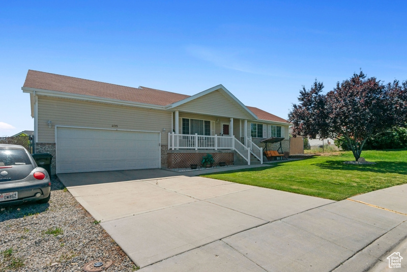 Ranch-style home featuring covered porch, a garage, a front lawn, and concrete driveway