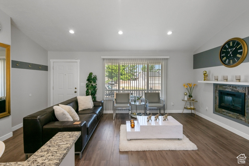 Living room featuring vaulted ceiling, dark wood-style floors, recessed lighting, and a glass covered fireplace