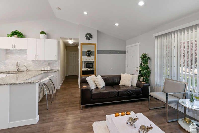 Living room with vaulted ceiling, dark wood-type flooring, and recessed lighting
