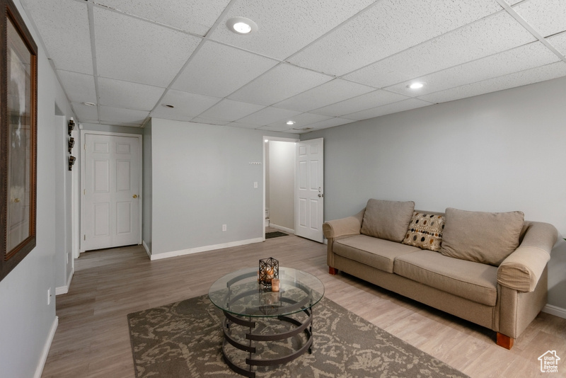 Living room with wood finished floors, a drop ceiling, and recessed lighting