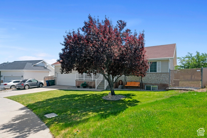 Obstructed view of property featuring driveway, brick siding, an attached garage, and a porch