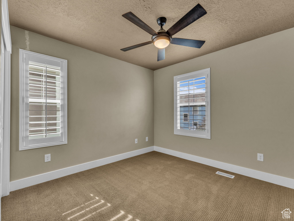 Carpeted spare room with a ceiling fan and a textured ceiling