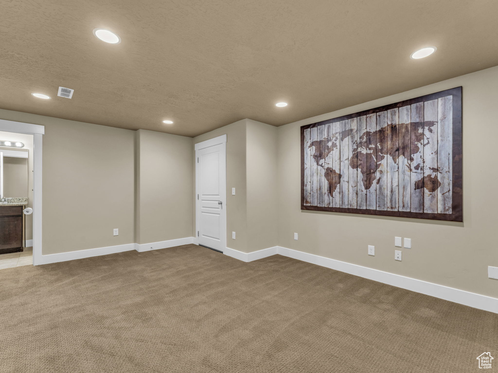 Basement featuring dark colored carpet, recessed lighting, and a textured ceiling