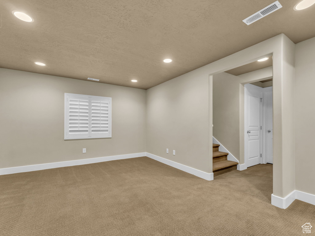 Carpeted empty room featuring recessed lighting, a textured ceiling, and stairs