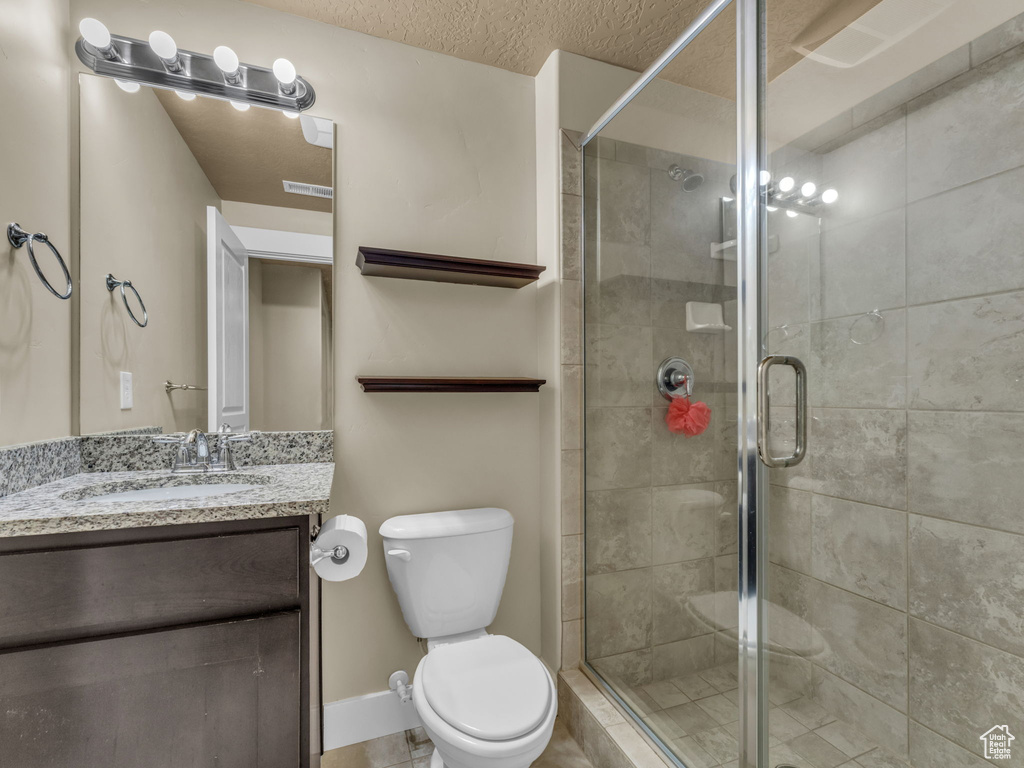 Bathroom with vanity, a shower stall, and a textured ceiling