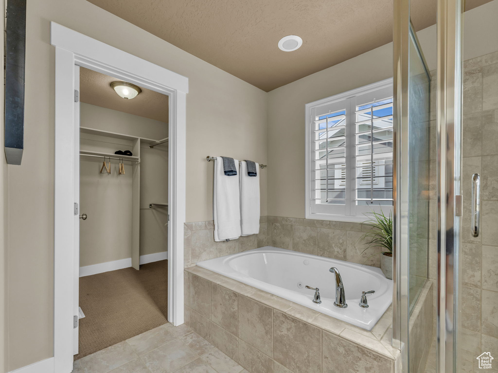 Bathroom with a bath, a walk in closet, a shower stall, and tile patterned flooring
