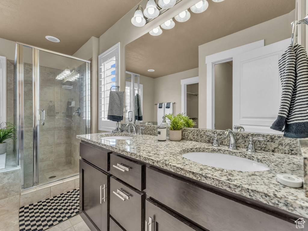 Full bathroom with a shower stall, double vanity, and tile patterned flooring